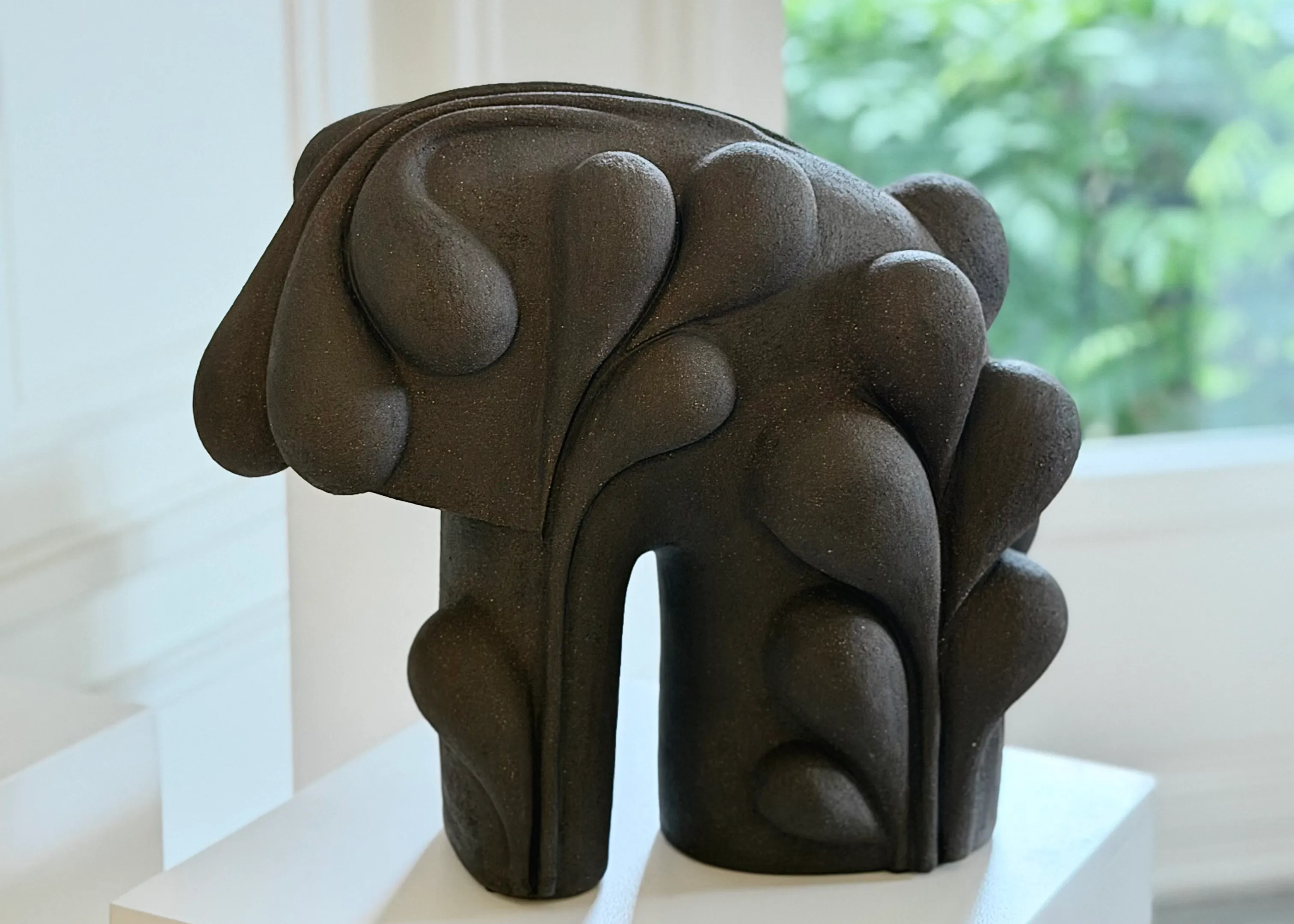 Sculpture en grès noir brut d'Elisa Uberti, céramiste exposée sur un socle blanc exposée à Villa Sonneville, maison galerie d'art datant de 1926