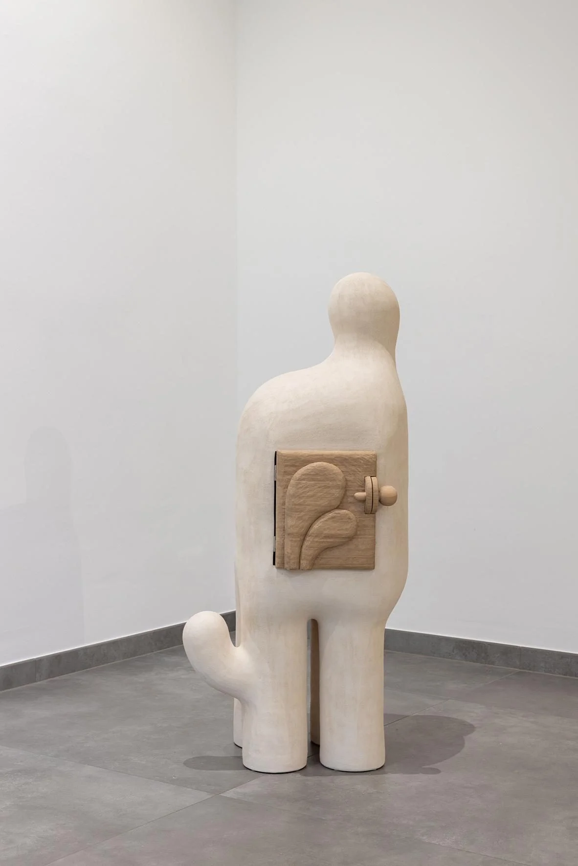 Sculpture Artemis #1 d'Elisa Uberti, meuble-cabinet en grès blanc en forme de silhouette debout, avec une petite porte en chêne massif ornée d'un motif végétal incrusté dans le dos.