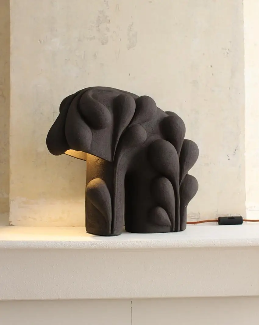Lampe Nature Boy #1 d'Elisa Uberti en grès noir, sculpture évoquant un feuillage dense et sombre, lumière chaude s'échappant de la base.