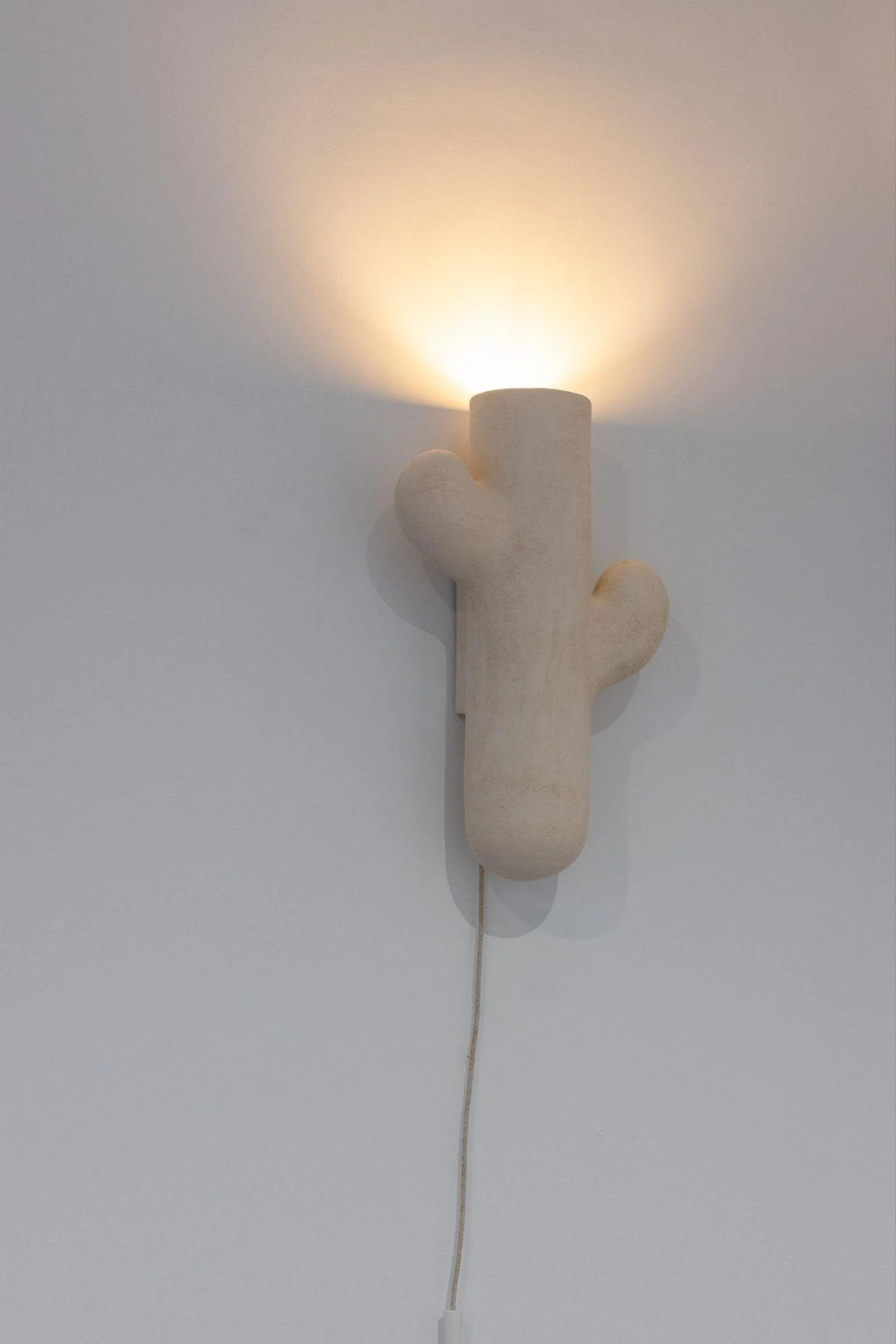 Applique murale Sconce Orée #3 d'Elisa Uberti en grès blanc, petite forme en cactus fixée au mur, éclairage doux dirigé vers le haut.