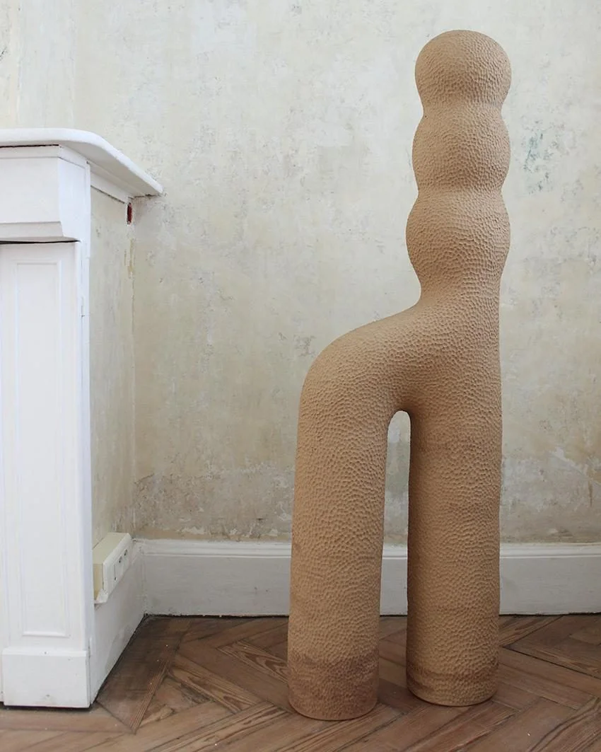 Sculpture Infini #3 d'Elisa Uberti en grès gingerbread, silhouette anthropomorphe à la texture martelée, deux jambes arquées et un buste segmenté en boules superposées.