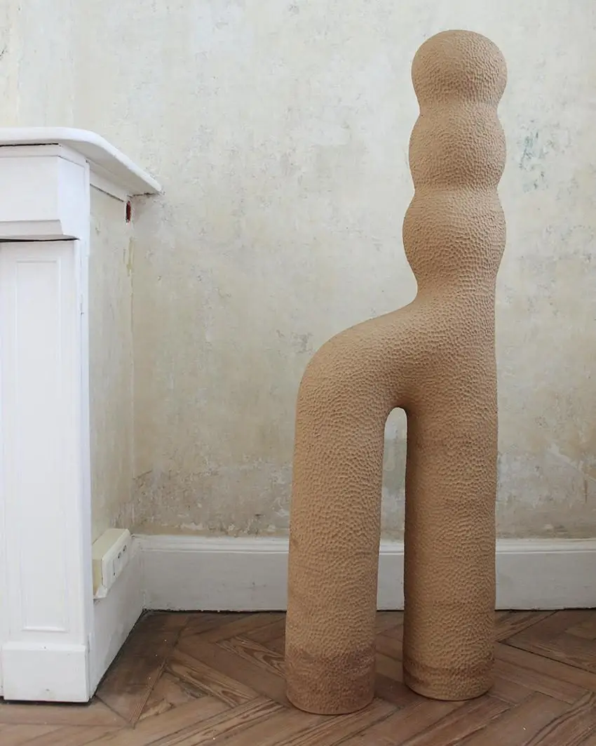 Sculpture Infini #3 d'Elisa Uberti en grès gingerbread, silhouette anthropomorphe à la texture martelée, deux jambes arquées et un buste segmenté en boules superposées.